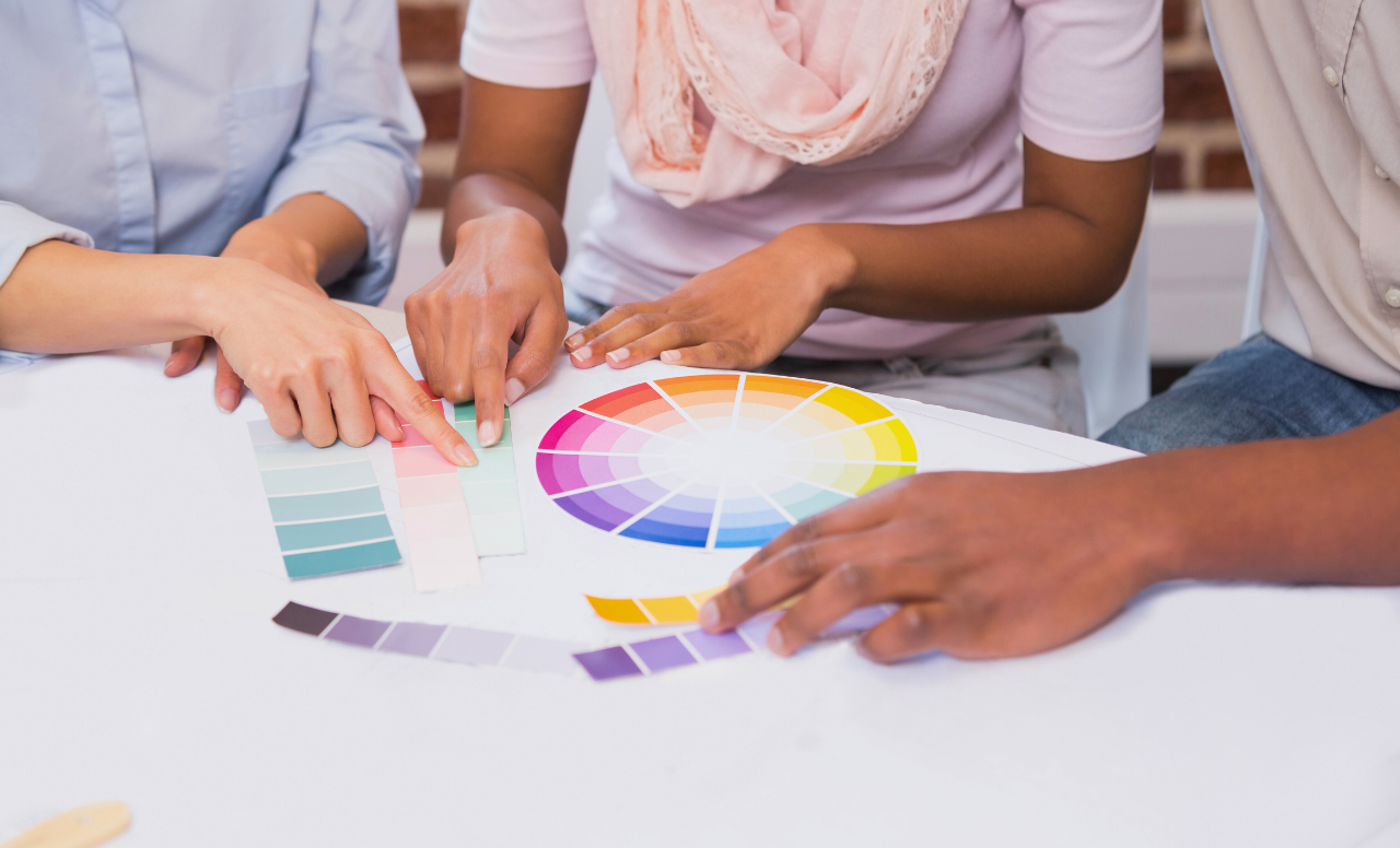 Trois personnes choisissent ensemble des teintes sur nuancier et cercle chromatique.